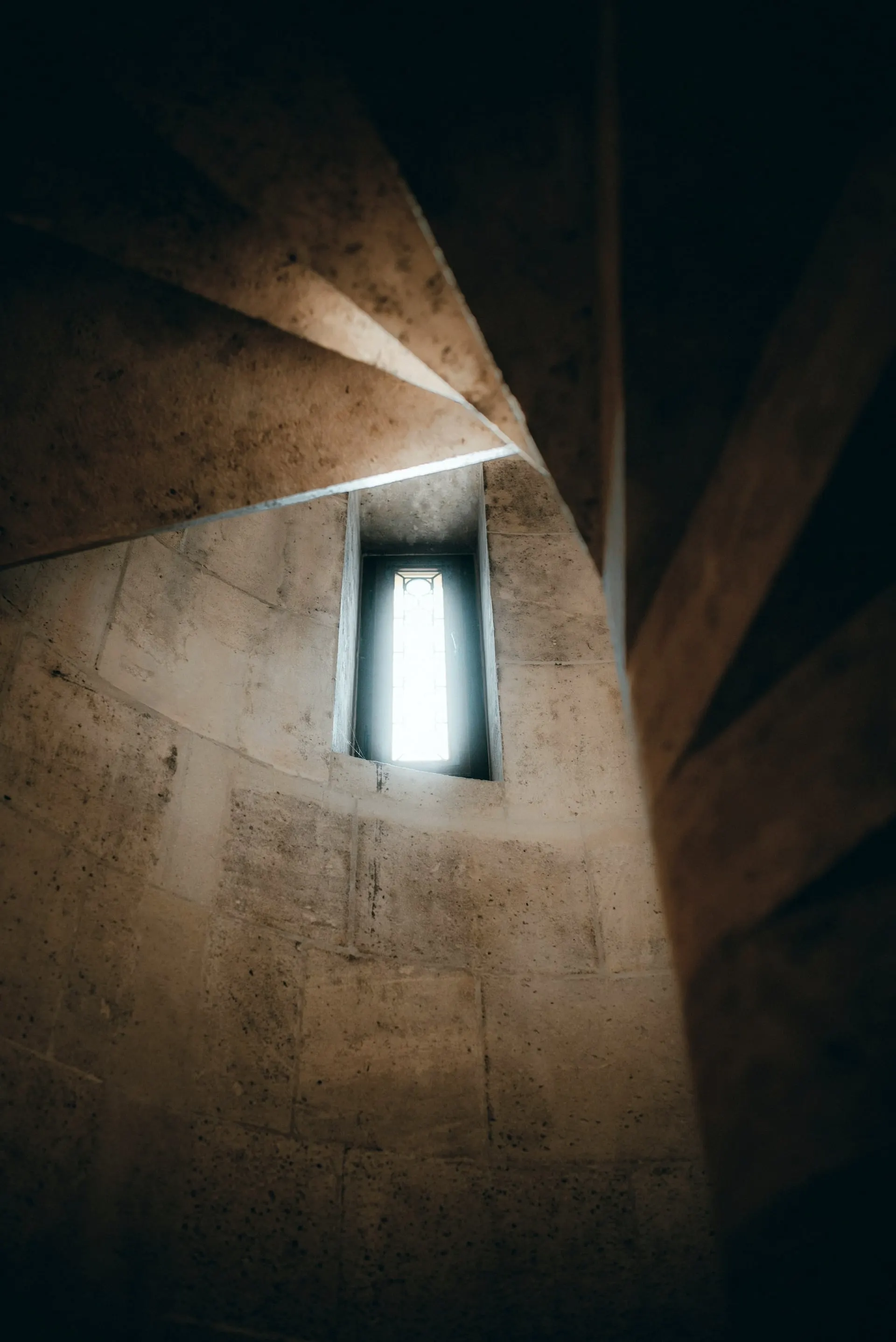 Cage d'escalier en pierre de taille, fenêtre étroite laissant passer la lumière